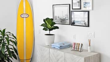 Une planche de surf, une plante en pot et un mur orné de tableaux.