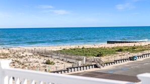 A beach view with a wooden fence, a parking area, and a clear blue sky. - The Hideaway Hotel (Beach Haven)