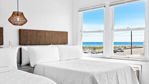 A hotel room with a large window offering a view of the beach and ocean. - The Hideaway Hotel (Beach Haven)