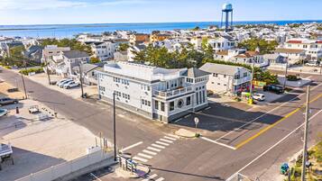A coastal town with a prominent white building with a balcony, a water tower, and a clear view of the ocean.