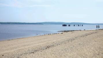 Une plage avec un rivage sablonneux et une jetée qui s’avance dans l’eau.