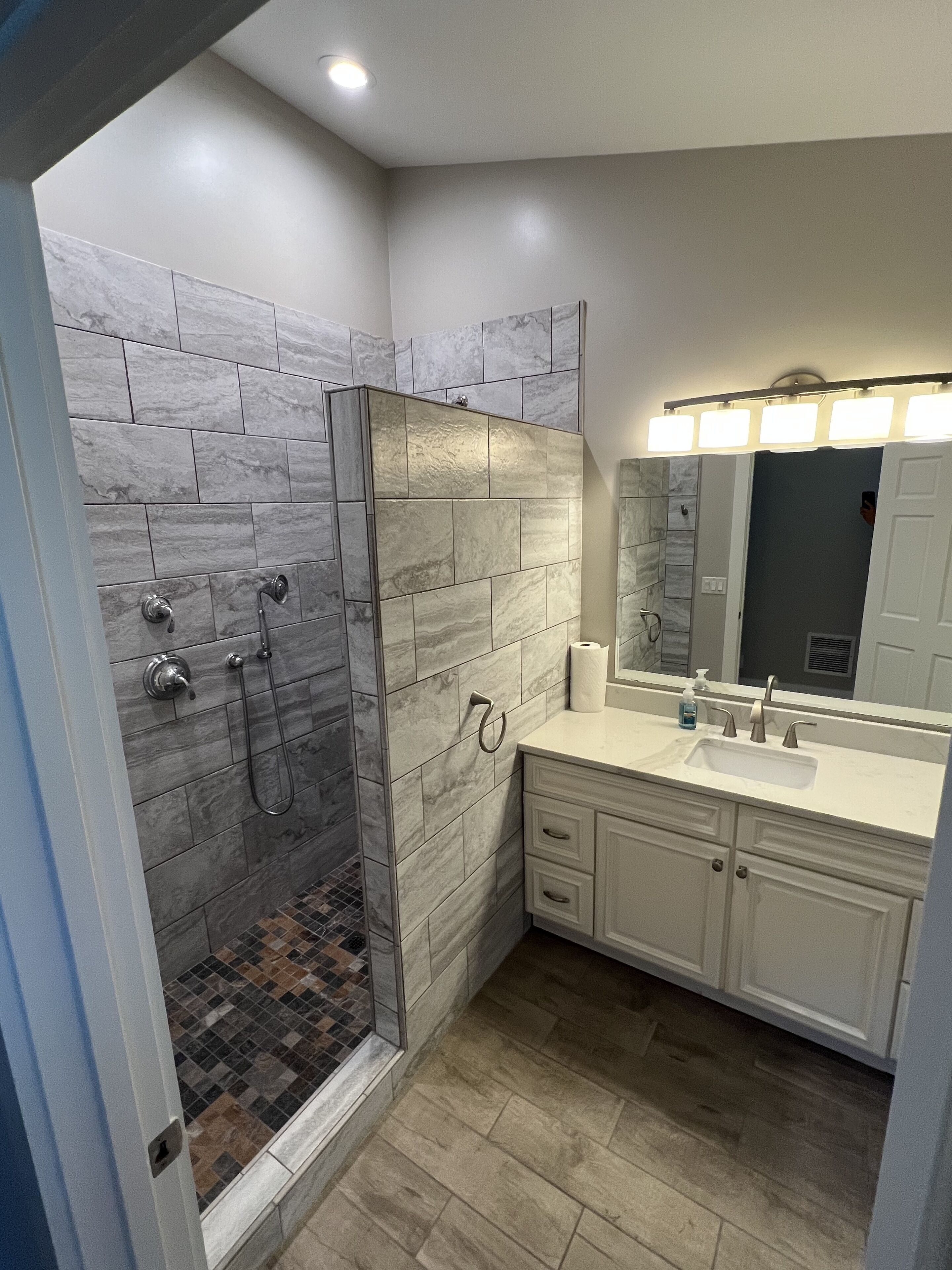 Un baño moderno con ducha envuelta en vidrio, tocador con espejo y lavabo.