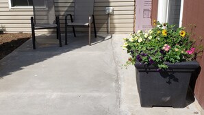 A house exterior with a concrete porch, two chairs, a flower planter, and a door with a sign. - Rural Somerset Get-A-Way (New Richmond)