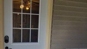 A white door with a window, a remote control on the door, and a wooden bench outside. - Rural Somerset Get-A-Way (New Richmond)