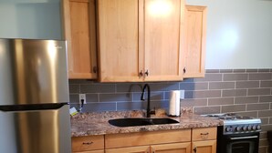 A kitchen with wooden cabinets, a stainless steel refrigerator, a sink, and a stove. - Rural Somerset Get-A-Way (New Richmond)