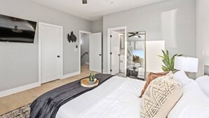 A modern bedroom with a large bed, a ceiling fan, and a TV on the wall. - Entire Brand New Luxury Townhouse! #2 (San Diego)