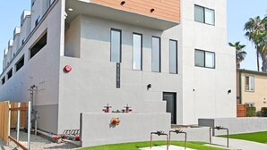 A modern building with a flat roof, large windows, and a small courtyard with artificial grass. - Entire Brand New Luxury Townhouse! #2 (San Diego)