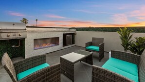 An outdoor patio with a grill, a fire pit, wicker furniture, and a view of the sunset. - Entire Brand New Luxury Townhouse! #2 (San Diego)