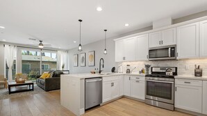 A modern kitchen with white cabinets, stainless steel appliances, and a large island. - Entire Brand New 2-Bedroom #5 Luxury Townhouse! (San Diego)
