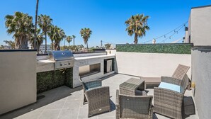 An outdoor patio with a grill, wicker furniture, and palm trees. - Entire Brand New 2-Bedroom #5 Luxury Townhouse! (San Diego)