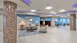 Un hall d’entrée spacieux avec un coin salon, un grand miroir et un mur d’accent bleu.
