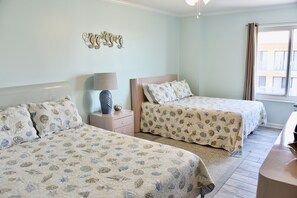 Une chambre avec deux lits, une table de chevet, une lampe et une fenêtre avec des rideaux.