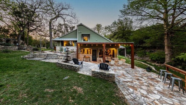 A house with a stone patio, outdoor seating, and a covered area with string lights. - River Run - Luxurious Adults Only Riverfront Oasis (Wimberley)