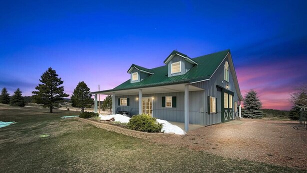A two-story house with a green roof and a covered porch. - Unique Barn Retreat by the Hills (Rapid City)