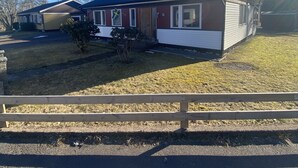 Een gelijkvloers huis met garage, schotelantenne en een kleine voortuin.