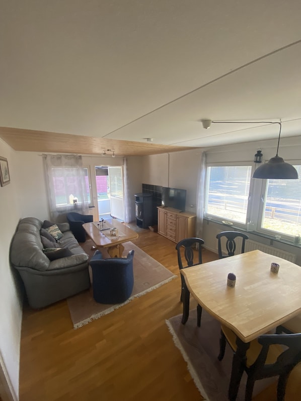 A living room with a sofa, a dining table, and a kitchen area with cabinets and a stove.