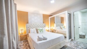 Une chambre d’hôtel moderne avec un grand lit, un miroir et une porte coulissante donnant sur la salle de bain.