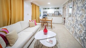 Un salon avec un canapé, une table basse sur laquelle se trouve un livre, et un coin repas avec une table et des chaises.