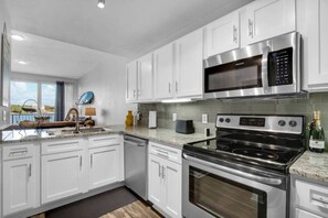 A modern kitchen with white cabinetry, stainless steel appliances, a built-in microwave, and a stove.