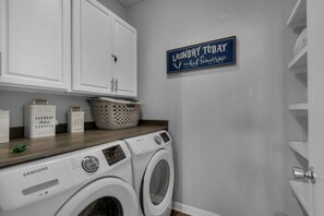 A laundry room with a Samsung washing machine, a basket, and a sign that reads 'Laundry Today'.