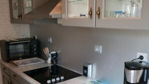 Eine Küche mit Mikrowelle, Toaster, Kaffeemaschine und einer Glastruhe mit Geschirr.