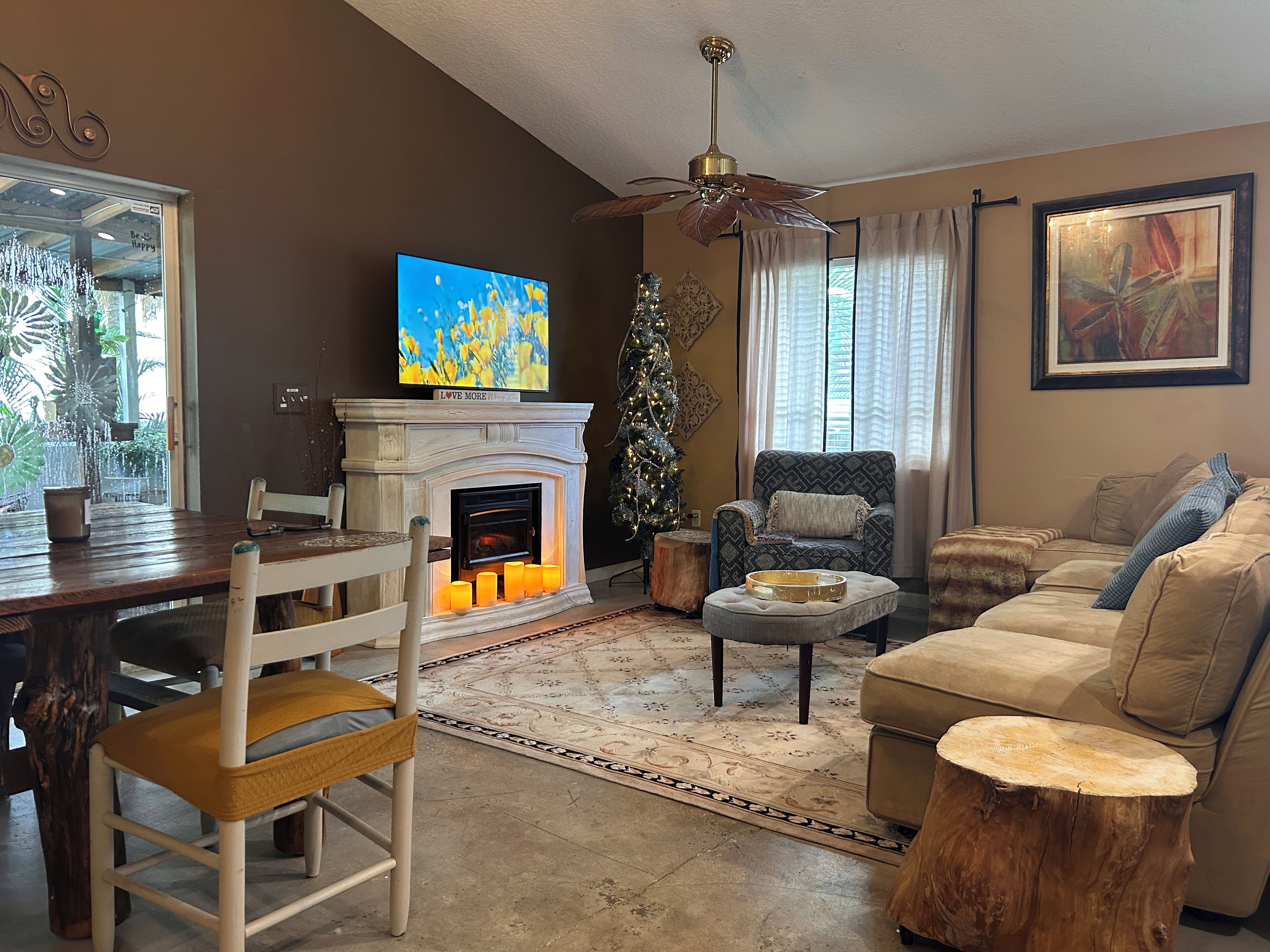 A cozy living room with a fireplace, a television, a Christmas tree, and a comfortable seating area.