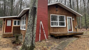 A cabin with a red exterior, a wooden deck, and a large window. - Cozy cottage just one mile from the Platte river, close to the Sleepy Bear dunes (Honor)