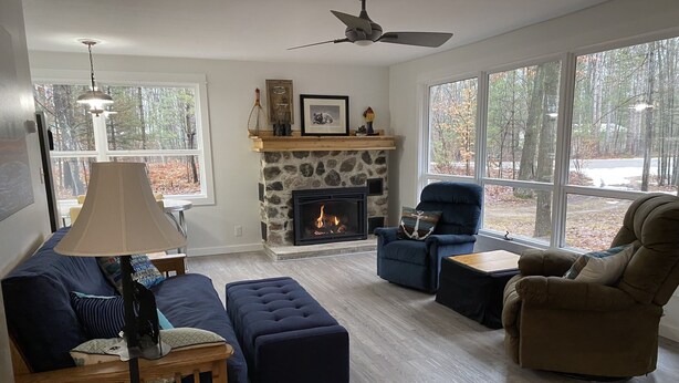 A living room with a stone fireplace, a blue armchair, a brown armchair, and a wooden coffee table. - Cozy cottage just one mile from the Platte river, close to the Sleepy Bear dunes (Honor)