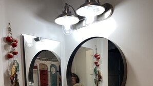 A bathroom with a white sink, a round mirror, and two wall-mounted lights. - Cozy cottage just one mile from the Platte river, close to the Sleepy Bear dunes (Honor)