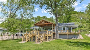 Une maison avec une terrasse en bois, un porche couvert et une cour clôturée.
