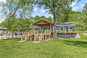 A house with a wooden deck, a covered porch, and a fenced yard.