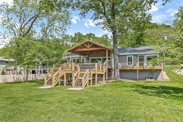 Ein Haus mit einer Holzdiele, einer Veranda und einem umzäunten Garten.