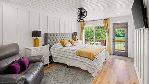 Une chambre à coucher avec un lit, une table de chevet, une lampe, un canapé et un téléviseur.