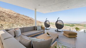 A modern outdoor seating area with a sofa, two woven chairs, and a wooden coffee table. - The Dream House - A Desert Masterpiece with Infinity Pool and Sauna (Palm Desert)