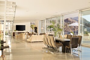 Ein modernes Wohnzimmer mit großem Fernseher, bequemen Sitzgelegenheiten und Blick auf die Berge.