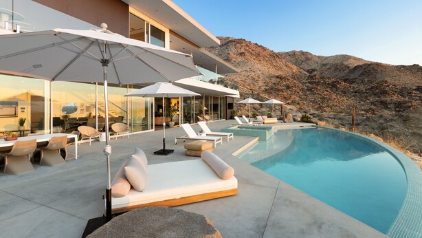 A modern outdoor pool area with lounge chairs and umbrellas, surrounded by a mountainous landscape. - The Dream House - A Desert Masterpiece with Infinity Pool and Sauna (Palm Desert)