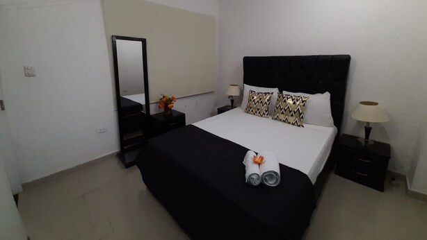 A hotel room with a bed, a nightstand, a lamp, a mirror, and an air conditioning unit. - 3G1-2 APARTAMENTO EN CARTAGENA (Cartagena)