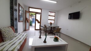 A living room with a sofa, a coffee table, a dining table with chairs, and a TV mounted on the wall. - 3G1-2 APARTAMENTO EN CARTAGENA (Cartagena)