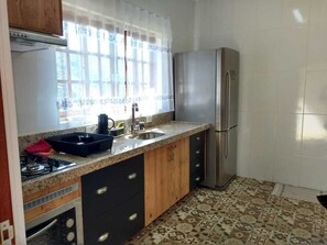 Una cocina con un refrigerador de acero inoxidable, un lavamanos y una estufa.