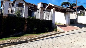 Rua residencial com casas, portão fechado e calçada.