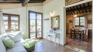 A spacious living area with a sofa, a dining table, and a kitchen in the background. - Casa Rialdo - Small family villa with private pool (Montecatini Val di Cecina)