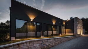 A modern building with large glass windows and stone accents. - Modern villa for 6 guests with pool, surrounded by pine forest, near beach (Valica)