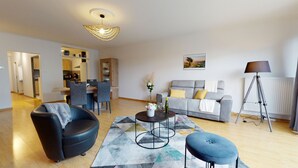 A modern living room with a sofa, a coffee table, and a dining area. - le nid cosy 1 free garage  up to 2 (Colmar)