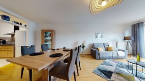 A modern living room with a wooden dining table, grey sofa, and a patterned rug. - le nid cosy 1 free garage  up to 2 (Colmar)