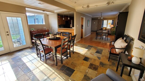 A spacious living area with a large wooden dining table, multiple chairs, and a cozy seating area with a sofa and armchairs.