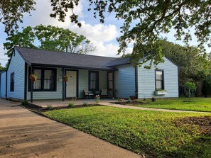 A single-story house with a front porch, a small garden, and a mailbox.