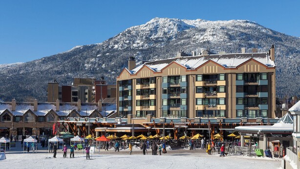 A hotel with a ski slope in the background, multiple floors, and a snow-covered mountain.