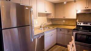 A modern kitchen with stainless steel appliances, a double sink, and light-colored cabinets. - The Rainbow Suite Mountain and Village View (Whistler)
