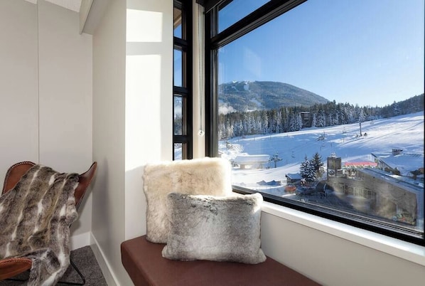 A window seat with a view of a snowy landscape and a mountain.