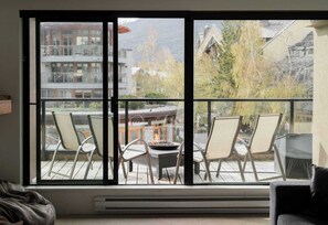 Habitación con un gran ventanal corredero que da a un patio exterior con sillas y una mesa.
